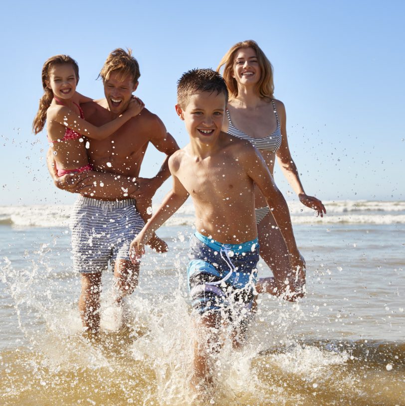 Family On Summer Beach Vacation Run Out Of Sea Towards Camera